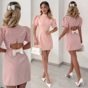 Mini Dress ALICE e sofisticato con maniche corte a sbuffo e una chiusura posteriore con bottoni rivestiti di perle, che aggiungono un tocco raffinato. La parte posteriore ha un'apertura che lascia intravedere la schiena, valorizzata da un fiocco
