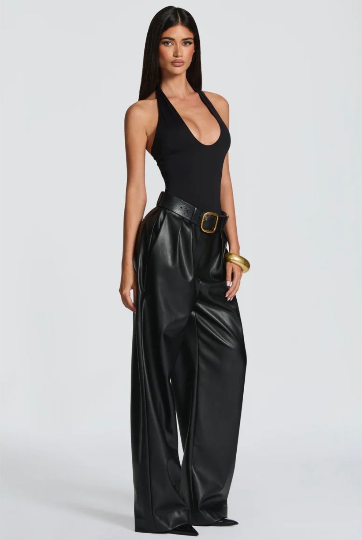 Pantalone Palazzo in Faux Leather Caratterizzato da una gamba ampia palazzo e doppie pinces frontali, dona un movimento sofisticato a ogni passo. La cintura sottile coordinata con fibbia metallica dorata definisce il punto vita.