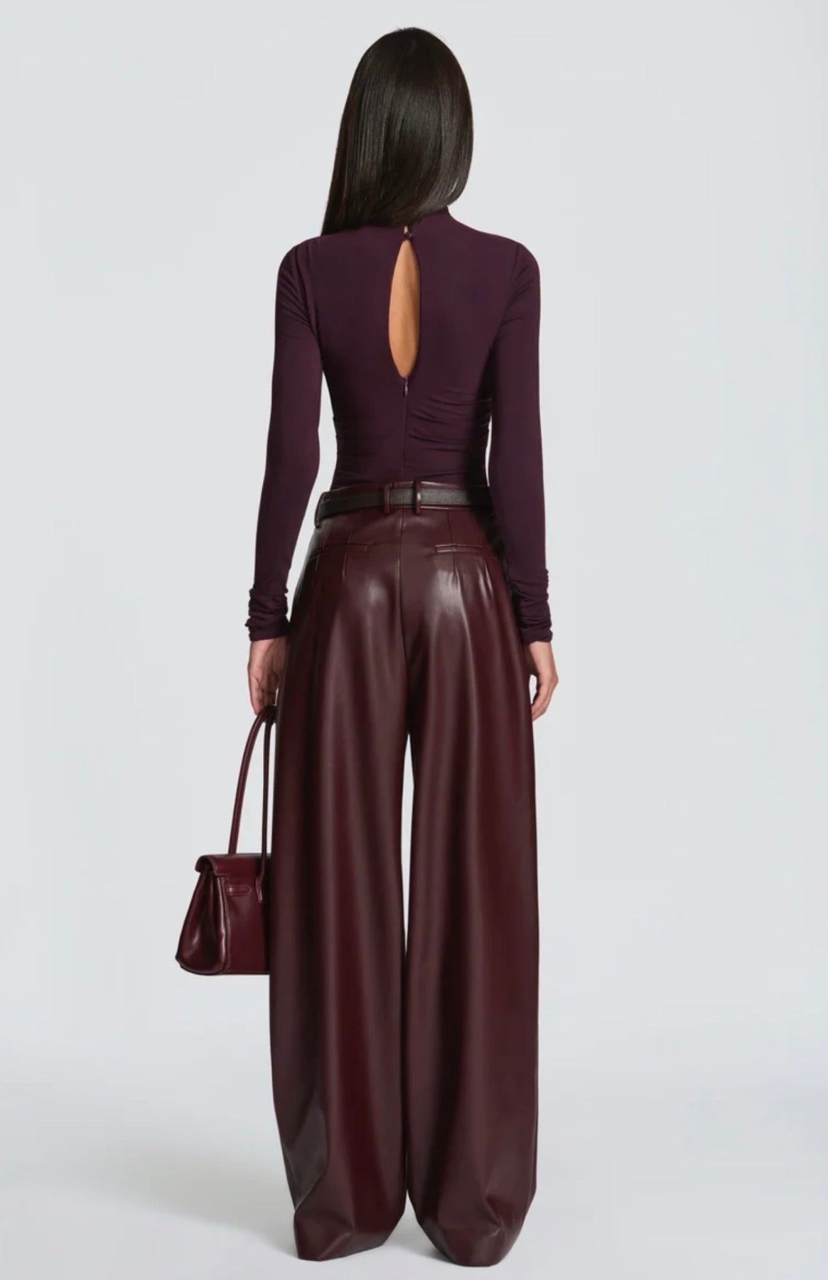 Pantalone Palazzo in Faux Leather Caratterizzato da una gamba ampia palazzo e doppie pinces frontali, dona un movimento sofisticato a ogni passo. La cintura sottile coordinata con fibbia metallica dorata definisce il punto vita.