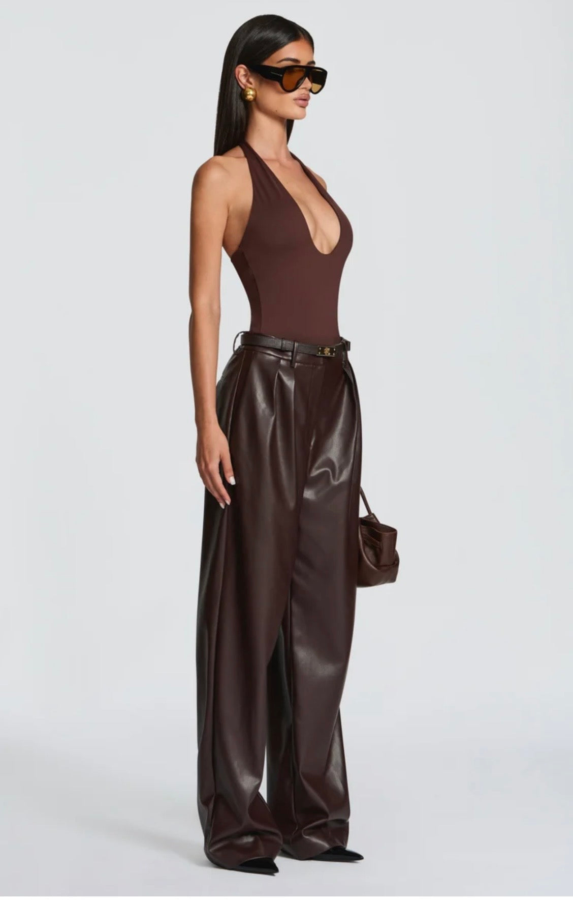 Pantalone Palazzo in Faux Leather Caratterizzato da una gamba ampia palazzo e doppie pinces frontali, dona un movimento sofisticato a ogni passo. La cintura sottile coordinata con fibbia metallica dorata definisce il punto vita.