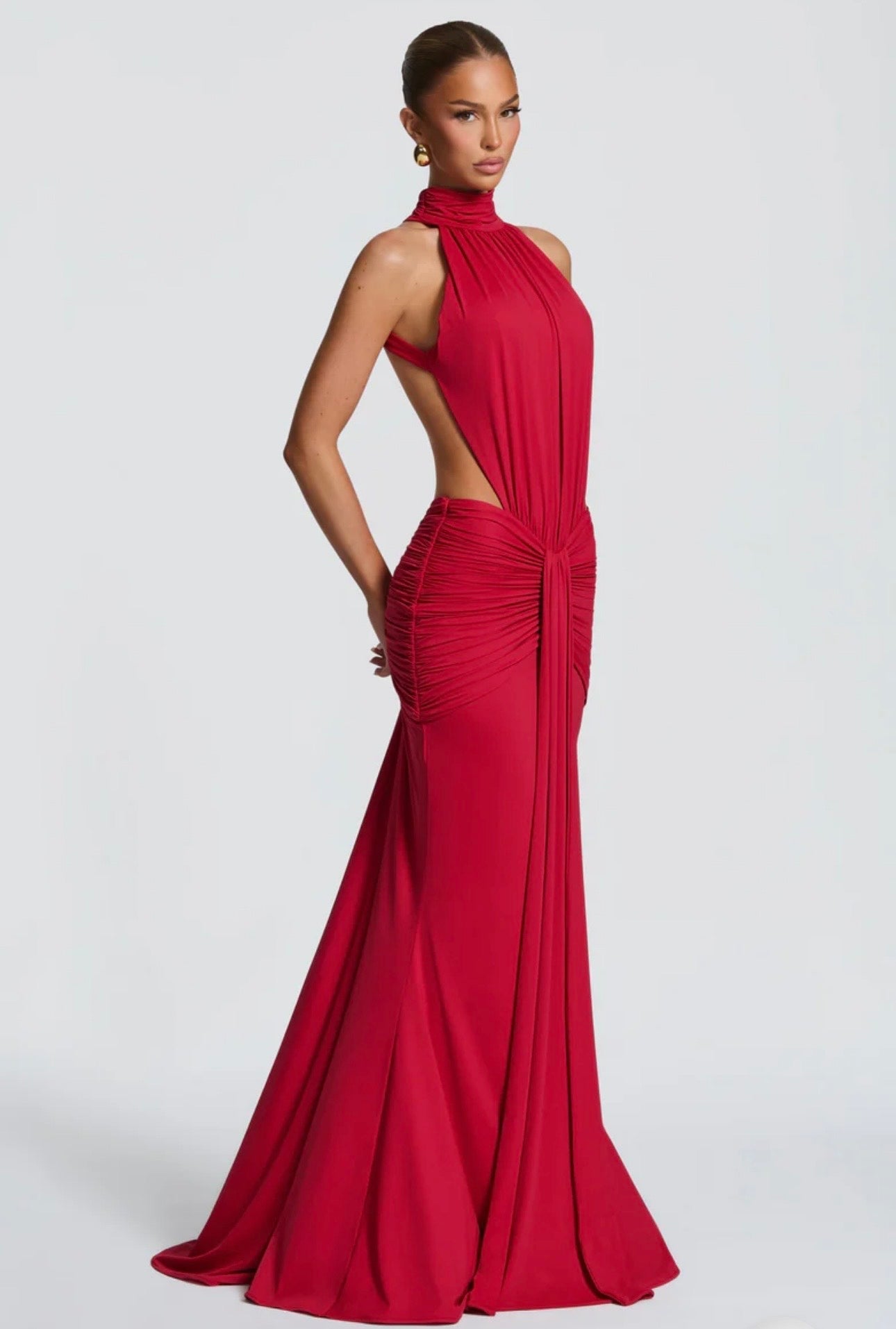 Abito Sofia Caratterizzato da una silhouette a sirena che valorizza le forme, questo modello unisce un sofisticato collo alto a un audace gioco di drappeggi e intagli cut-out sui fianchi.
