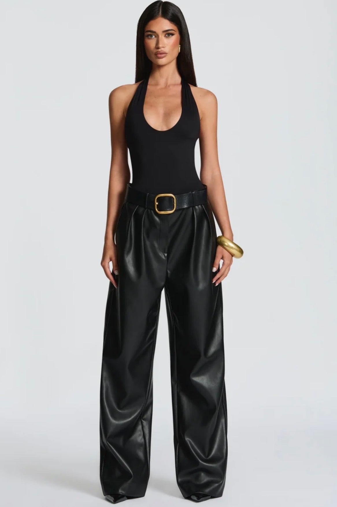 Pantalone Palazzo in Faux Leather Caratterizzato da una gamba ampia palazzo e doppie pinces frontali, dona un movimento sofisticato a ogni passo. La cintura sottile coordinata con fibbia metallica dorata definisce il punto vita.