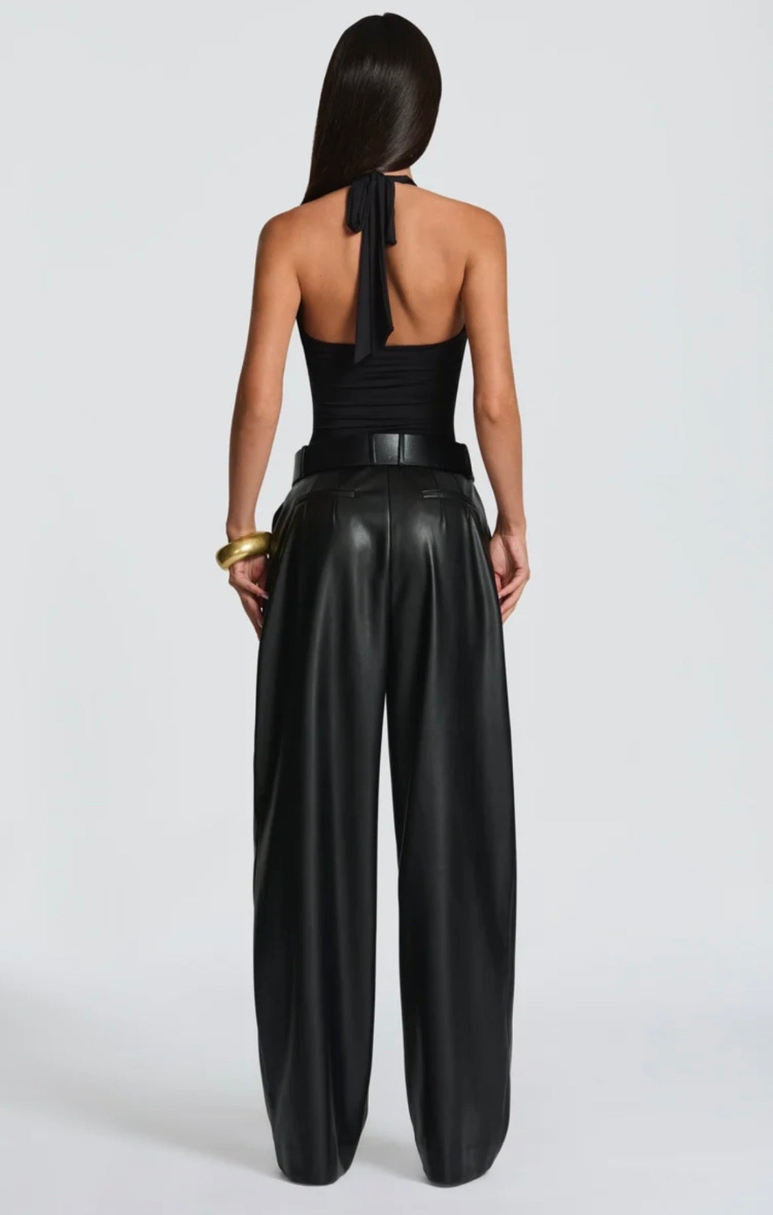 Pantalone Palazzo in Faux Leather Caratterizzato da una gamba ampia palazzo e doppie pinces frontali, dona un movimento sofisticato a ogni passo. La cintura sottile coordinata con fibbia metallica dorata definisce il punto vita.