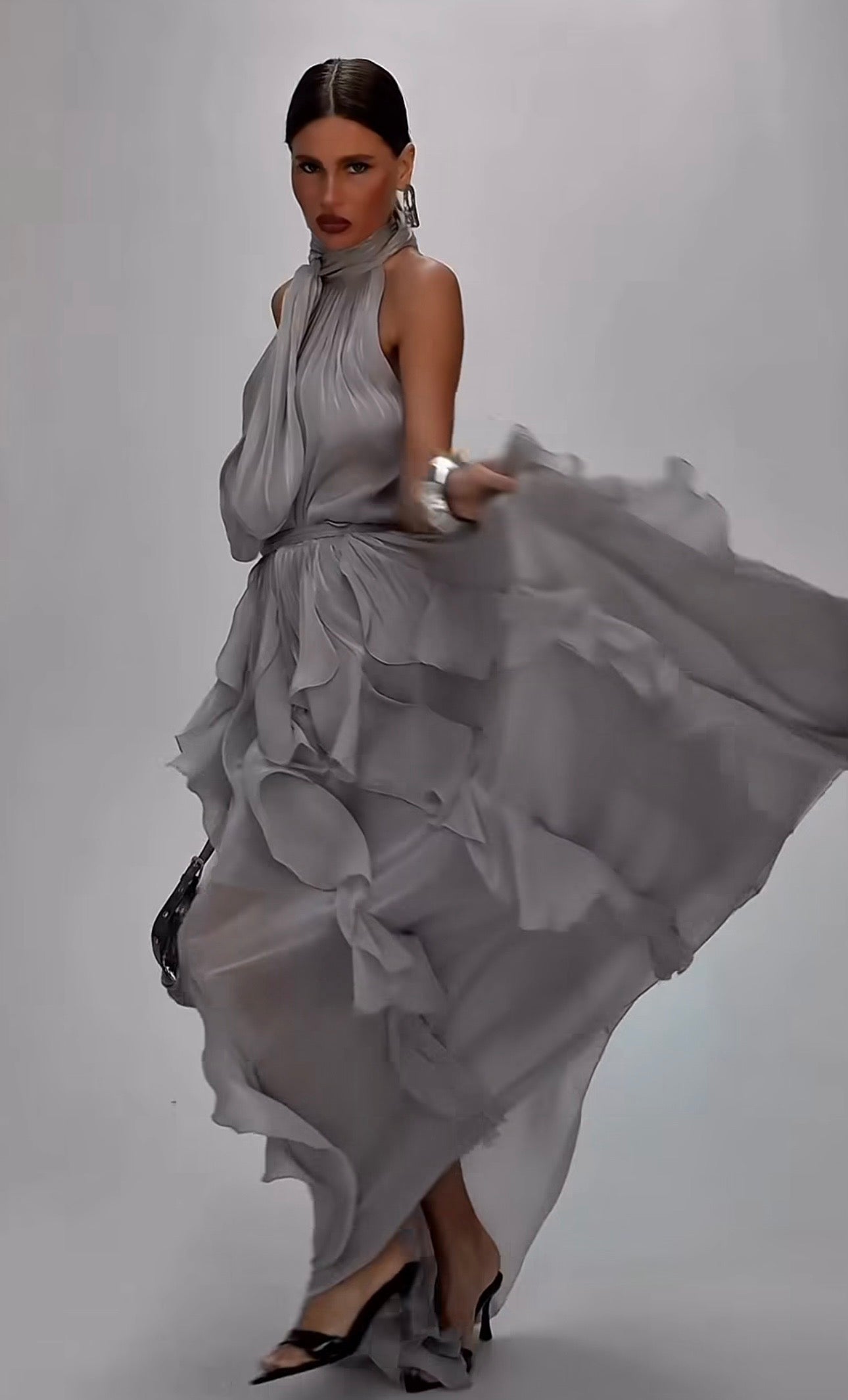 Abito Rouches maxi dress con scollo all'americana, collo con fiocco e gonna a cascata di rouches multistrato pensato per chi vuole essere al centro della scena senza sforzo. La silhouette fluida e il tessuto leggero lo rendono perfetto