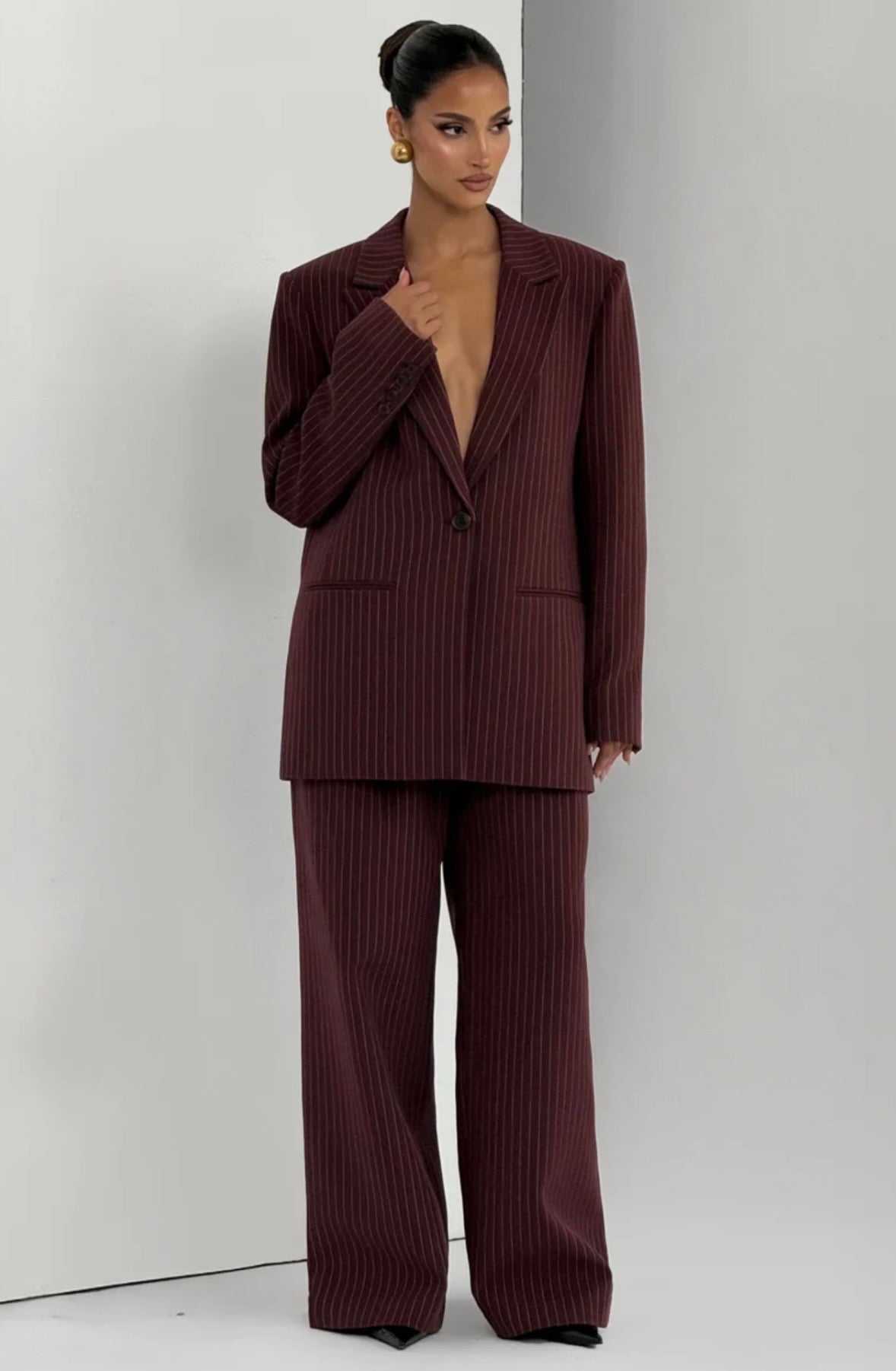 L'essenza del Tailleur Ilary contemporaneo gessato. Questo set coordinato combina un blazer monopetto strutturato a spalla definita con pantaloni palazzo a gamba larga caduta fluida. Il motivo gessato sottile regala una silhouette slanciata ed elegante