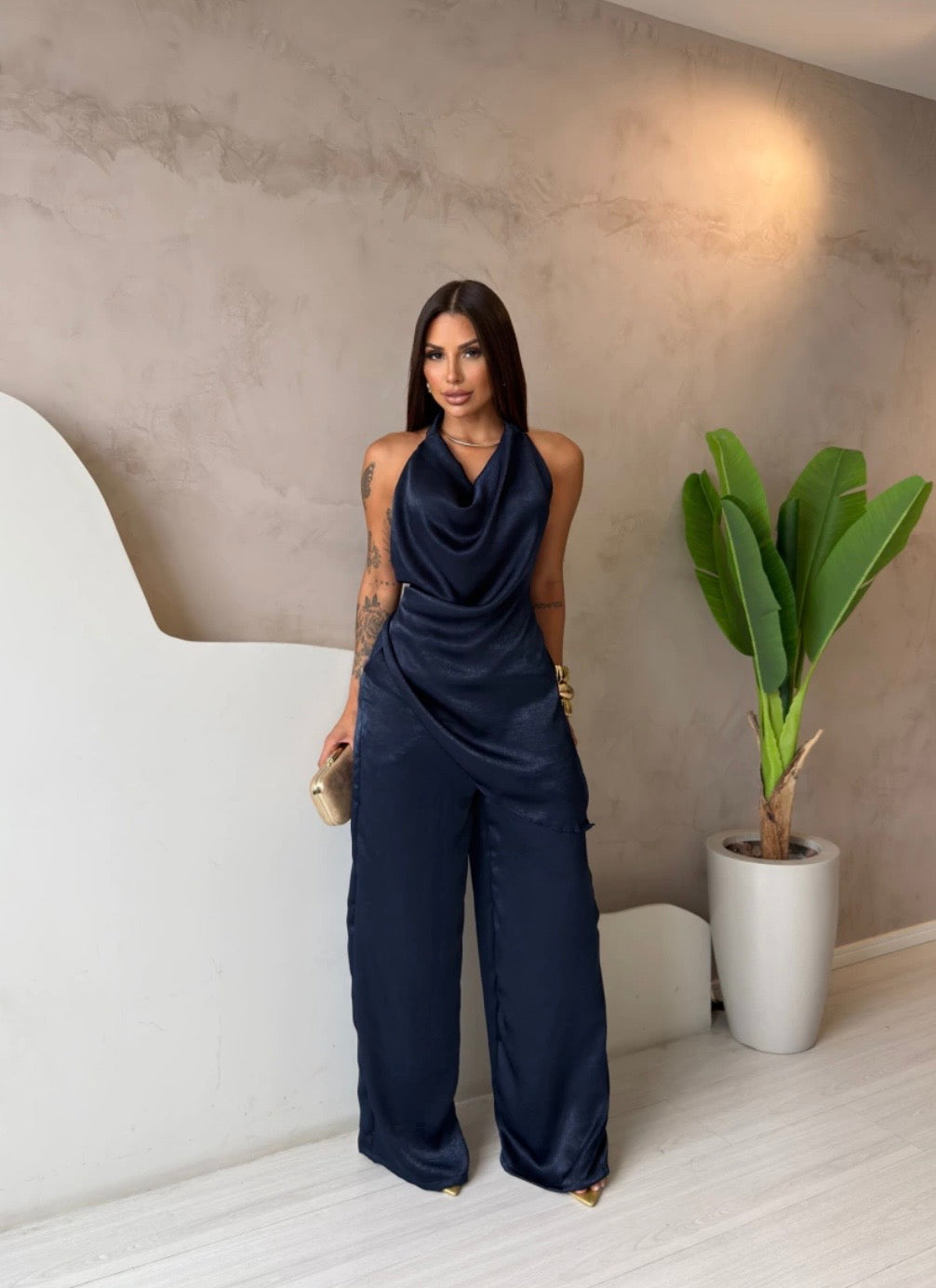 Coordinato Barbara Il set è composto di seta satinata da un top con scollo a cappuccio e schiena scoperta che valorizza la silhouette, abbinato a un pantalone a palazzo fluido che slancia la figura ad ogni passo.