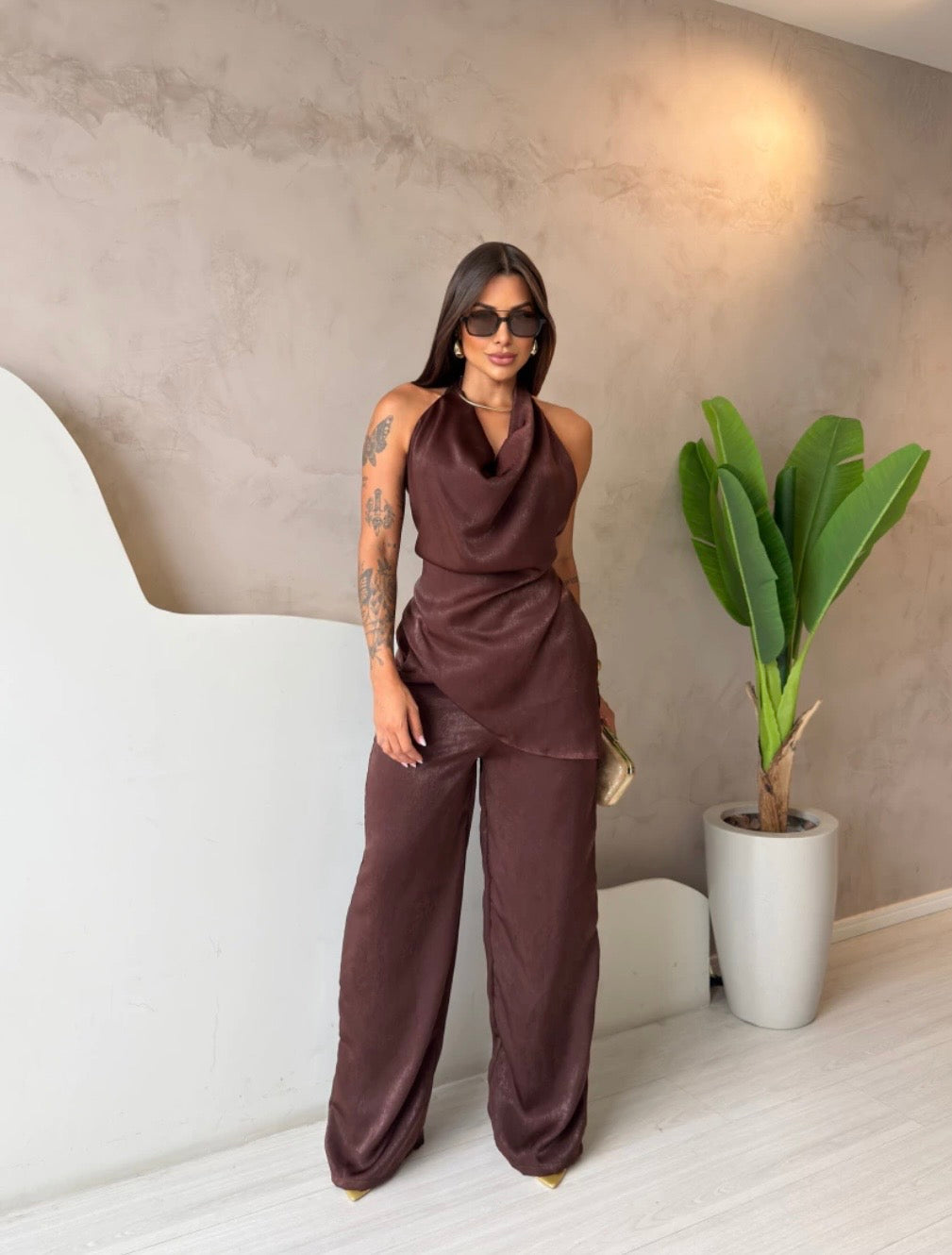 Coordinato Barbara Il set è composto di seta satinata da un top con scollo a cappuccio e schiena scoperta che valorizza la silhouette, abbinato a un pantalone a palazzo fluido che slancia la figura ad ogni passo.