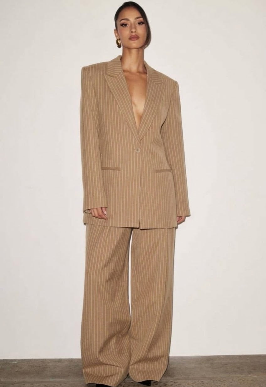 L'essenza del Tailleur Ilary contemporaneo gessato. Questo set coordinato combina un blazer monopetto strutturato a spalla definita con pantaloni palazzo a gamba larga caduta fluida. Il motivo gessato sottile regala una silhouette slanciata ed elegante