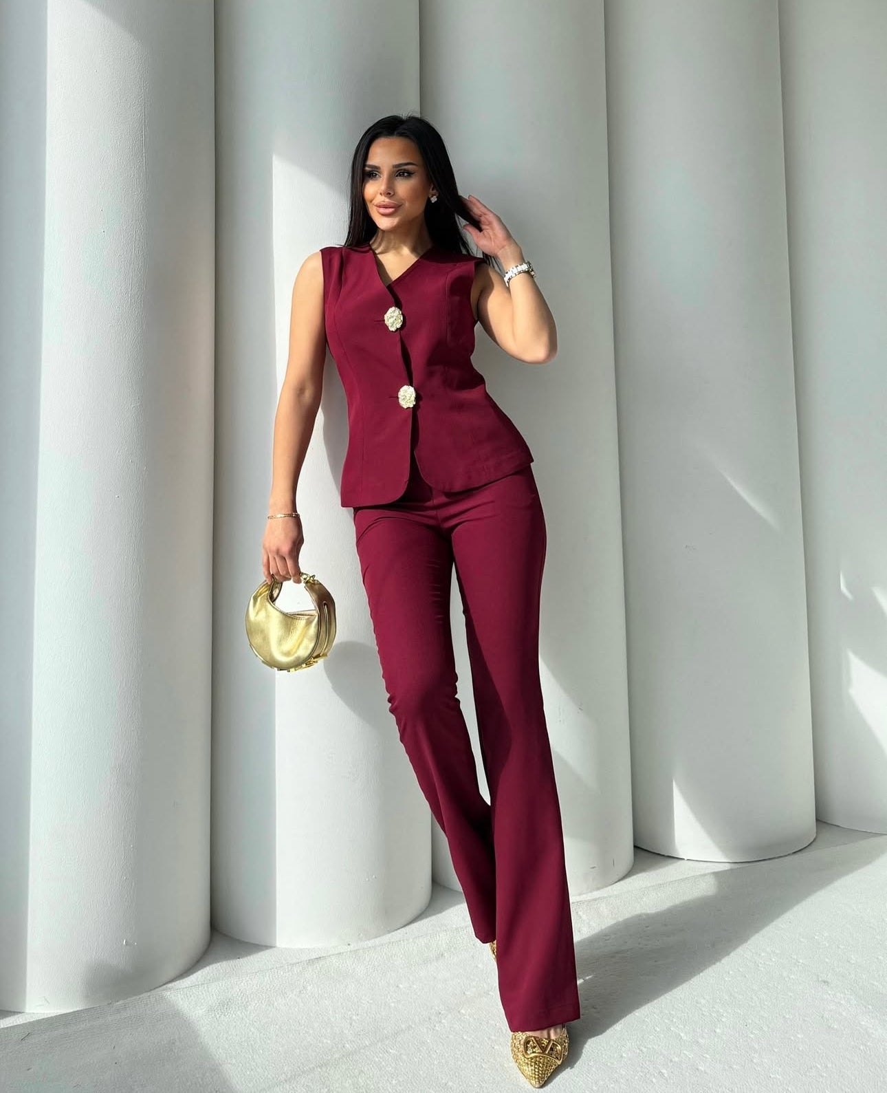 Set cord PERLA elegante composto da un gilet smanicato e un paio di pantaloni a gamba larga  Il gilet presenta due bottoni decorativi centrali dal design gioiello. I pantaloni sono a vita alta, con una vestibilità morbida e fluida
