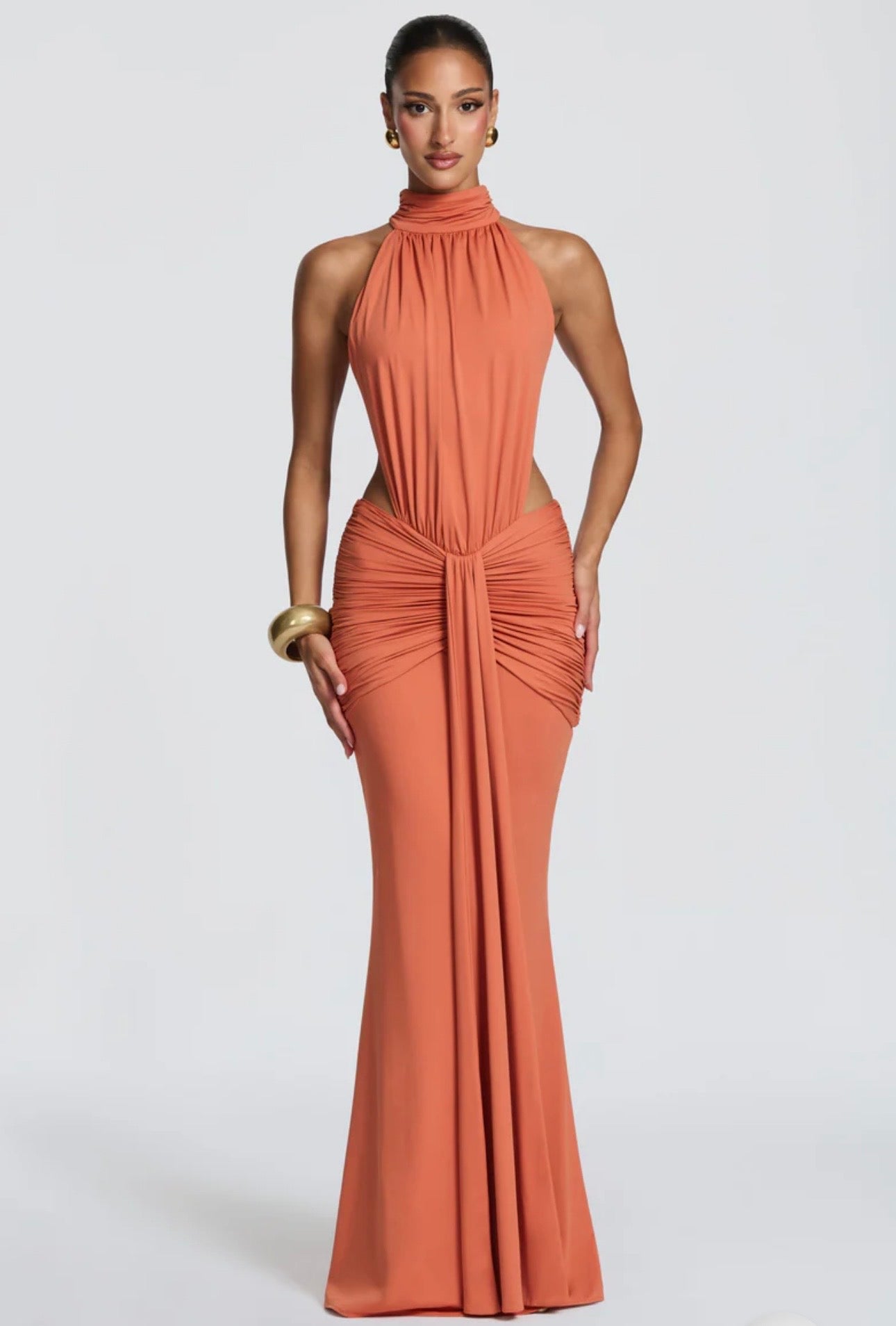 Abito Serena Caratterizzato da una silhouette a sirena che valorizza le forme, questo modello unisce un sofisticato collo alto a un audace gioco di drappeggi e intagli cut-out sui fianchi.