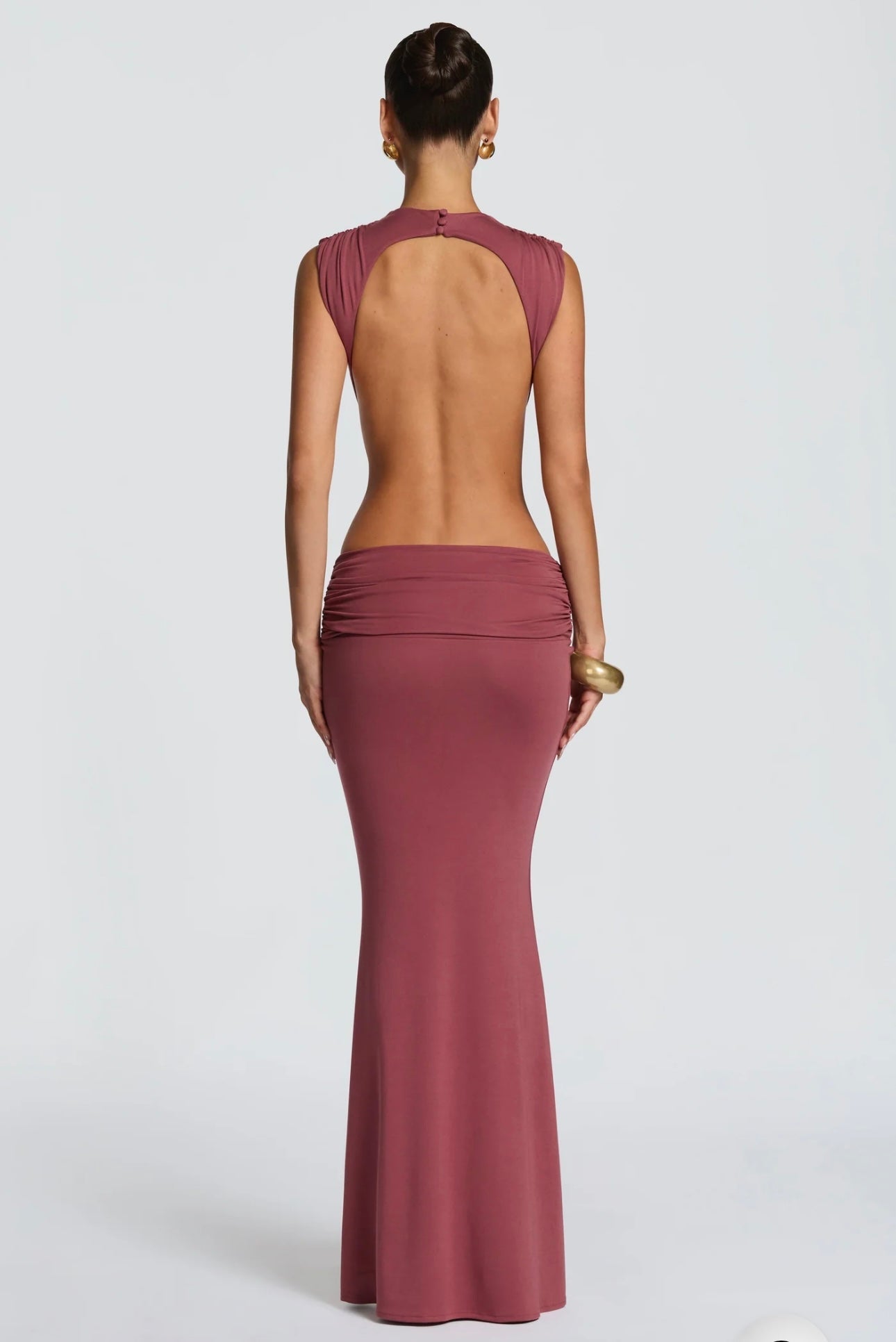 Abito Sahara maxi aderente in elegante rosa terracotta con design cut-out laterale che scolpisce la silhouette. Il collo alto crea un raffinato contrasto con le ampie aperture sui fianchi e la schiena scoperta, per un effetto sensuale ma sofisticato.