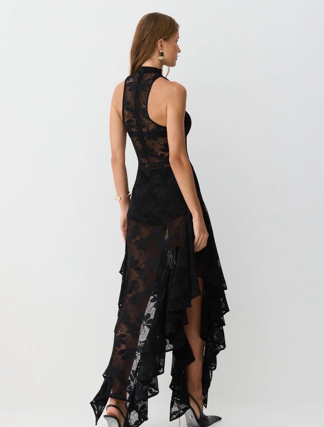 Abito Zaira in pizzo floreale semitrasparente con scollo halter e collo alto. La gonna asimmetrica a strati con orlo a fazzoletto conferisce movimento e carattere, mentre il corpino aderente valorizza la silhouette.