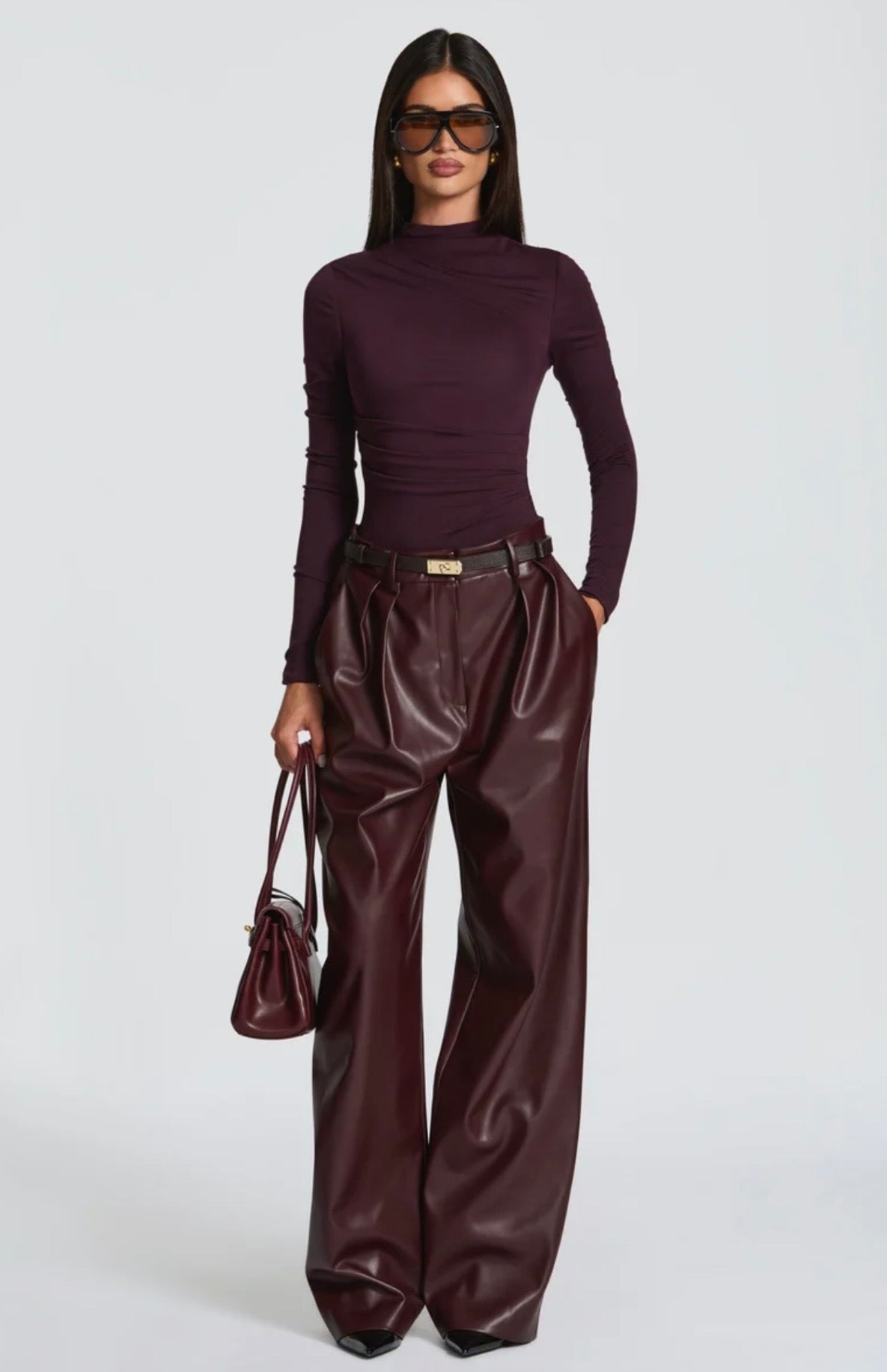 Pantalone Palazzo in Faux Leather Caratterizzato da una gamba ampia palazzo e doppie pinces frontali, dona un movimento sofisticato a ogni passo. La cintura sottile coordinata con fibbia metallica dorata definisce il punto vita.