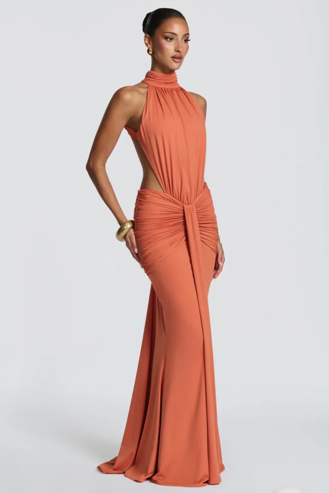 Abito Serena Caratterizzato da una silhouette a sirena che valorizza le forme, questo modello unisce un sofisticato collo alto a un audace gioco di drappeggi e intagli cut-out sui fianchi.