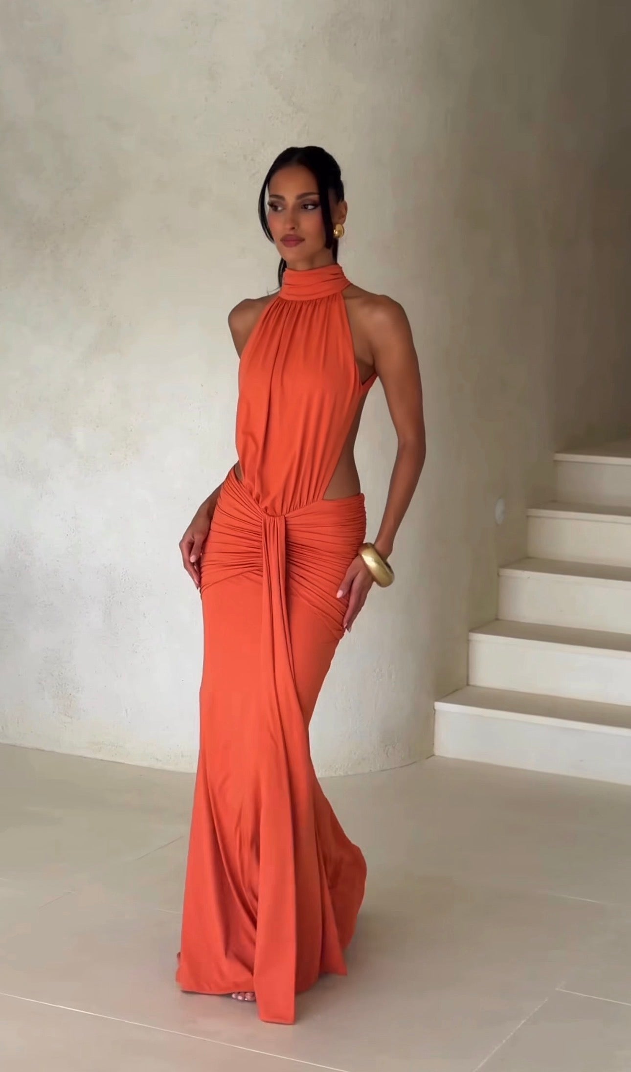 Abito Serena Caratterizzato da una silhouette a sirena che valorizza le forme, questo modello unisce un sofisticato collo alto a un audace gioco di drappeggi e intagli cut-out sui fianchi.