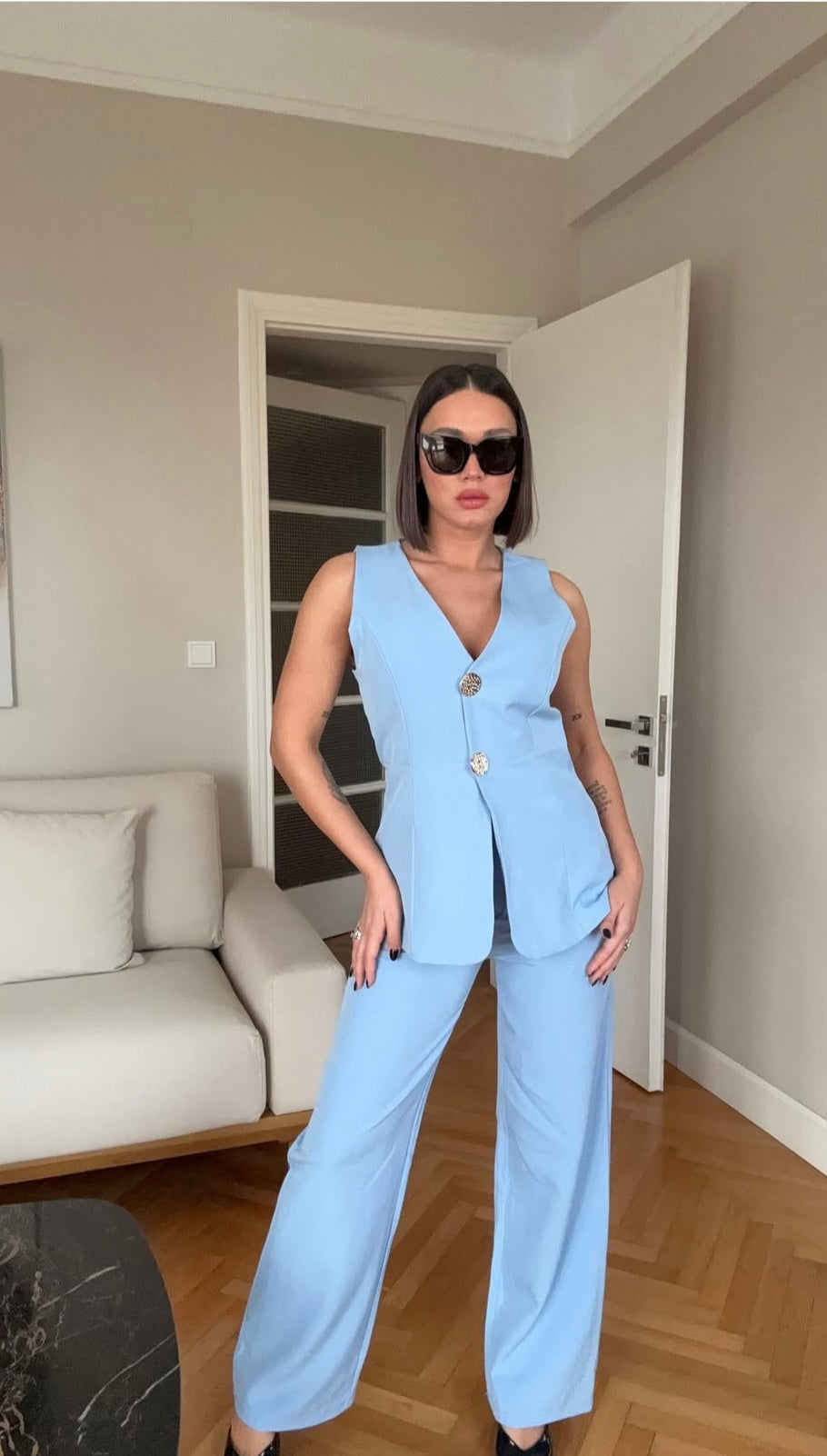Tailleur ESTER elegante composto da un gilet smanicato e un paio di pantaloni a gamba larga  Il gilet presenta due bottoni decorativi centrali dal design gioiello. I pantaloni sono a vita alta, con una vestibilità morbida e fluida