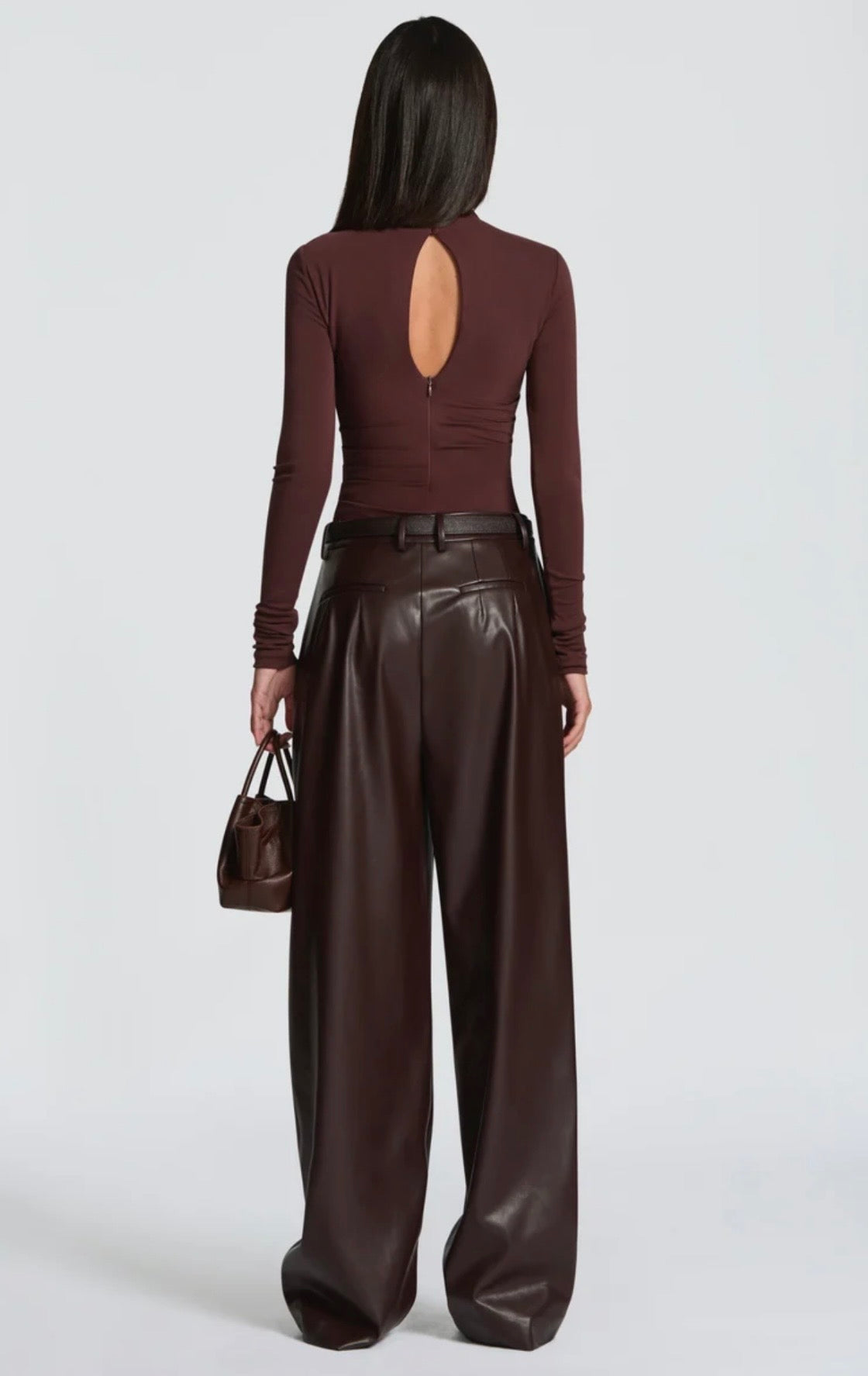 Pantalone Palazzo in Faux Leather Caratterizzato da una gamba ampia palazzo e doppie pinces frontali, dona un movimento sofisticato a ogni passo. La cintura sottile coordinata con fibbia metallica dorata definisce il punto vita.