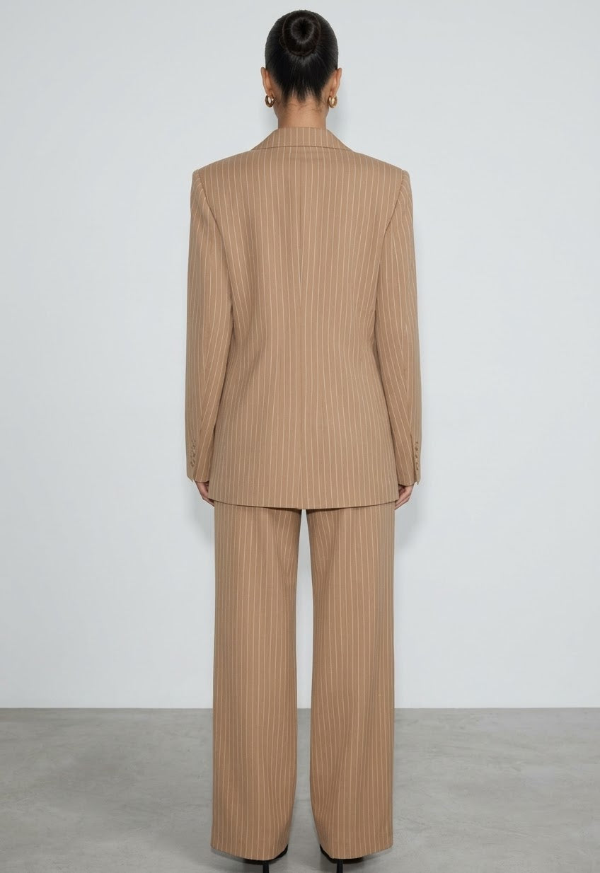 L'essenza del Tailleur Ilary contemporaneo gessato. Questo set coordinato combina un blazer monopetto strutturato a spalla definita con pantaloni palazzo a gamba larga caduta fluida. Il motivo gessato sottile regala una silhouette slanciata ed elegante